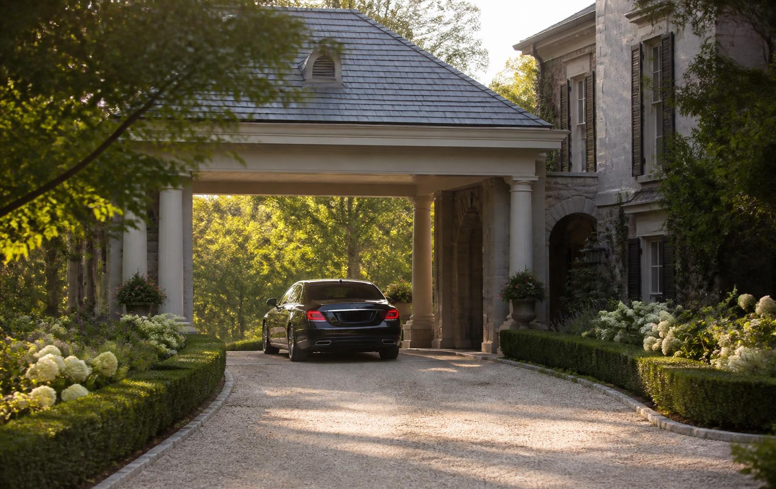 Manicured grounds and covered entry of a luxury residence with a car arriving